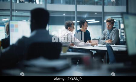Équipe diversifiée de gestionnaires travaillant et ayant des discussions dans le bureau moderne de la grande ville. Les employés travaillent sur de nouvelles opportunités commerciales, le conseil d'administration tient une réunion, parle d'investir dans l'avenir. Banque D'Images
