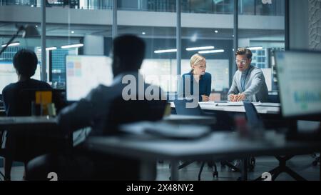 Équipe diversifiée de gestionnaires travaillant et ayant des discussions dans le bureau moderne de la grande ville. Les employés travaillent sur de nouvelles opportunités commerciales, le PDG rencontre l'employé et parle d'investir dans l'avenir. Banque D'Images