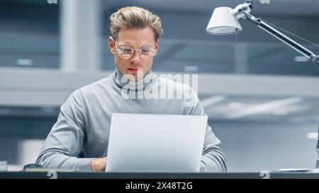 Bureau moderne : homme d'affaires assis à son bureau travaillant sur un ordinateur portable. Entrepreneur numérique travaillant avec Big Data e-commerce Project, démarrage réussi. Arrière-plan flou. Banque D'Images