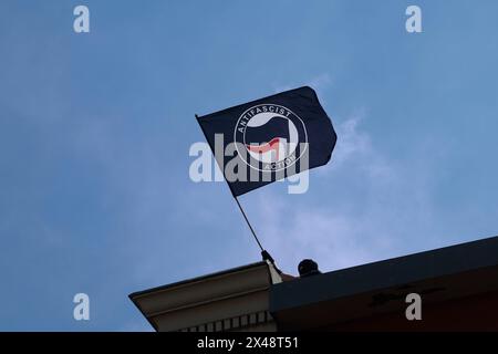 Hambourg, Allemagne. 01 mai 2024. Un homme masqué agite un drapeau antifasciste lors d'une manifestation de groupes de gauche le 1er mai à la Rote Flora dans le Schanzenviertel. Crédit : Axel Heimken/dpa/Alamy Live News Banque D'Images