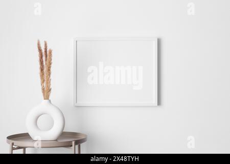 Maquette de cadre blanc sur le mur avec une décoration de pampas. Banque D'Images