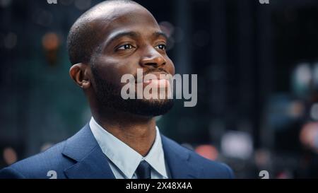Portrait d'homme d'affaires noir réfléchi portant un costume, debout dans la rue du quartier des affaires de Big City, posant et souriant. Entrepreneur numérique afro-américain prospère Banque D'Images