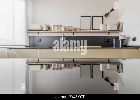 Une façade d'une cuisine avec des étagères pleines de condiments et leur reflet dans une plaque vitrocéramique Banque D'Images