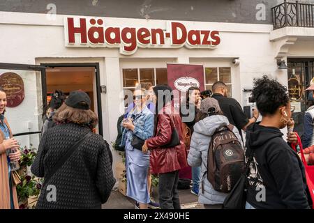 Les gens s’alignent pour des boules gratuites de crème glacée HŠagen-Dazs célébrant la réouverture de leur magasin à Brooklyn Heights à New York le samedi 27 avril 2024. Le magasin est le premier magasin ouvert par la société de crème glacée, en 1976. HŠagen-Dazs est une marque de General Mills. ( © Richard B. Levine) Banque D'Images