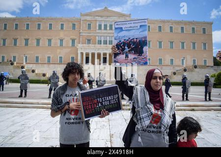 Athènes, Grèce. 1er mai 2024. Une femme tient une pancarte avec des slogans devant le Parlement grec en solidarité avec les Palestiniens concernant la guerre d'Israël à Gaza. Des milliers de personnes protestent contre « les prix élevés et la perte de salaires qui conduisent la société à un appauvrissement permanent » lors des rassemblements du 1er mai. Crédit : Dimitris Aspiotis/Alamy Live News Banque D'Images