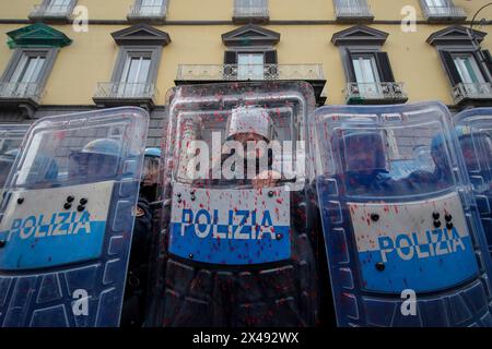 Naples, Italie. 01 mai 2024. Le personnel de police couvert de peinture rouge alors que les manifestants lançaient de la peinture rouge sur la porte d'entrée du siège de l'Union industrielle pendant la procession de la fête du travail. Crédit : Agence photo indépendante/Alamy Live News Banque D'Images