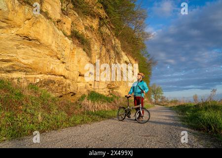 Cycliste masculin senior chevauchant un vélo pliant sur Steamboat trace, piste cyclable convertie à partir d'un chemin de fer abandonné, près du Pérou, Nebraska, matin de printemps Banque D'Images