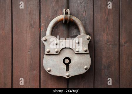 Vieux cadenas rouillé sur une porte en bois. Porte en bois avec grande serrure en fer à charnières dans le village. vue rapprochée Banque D'Images