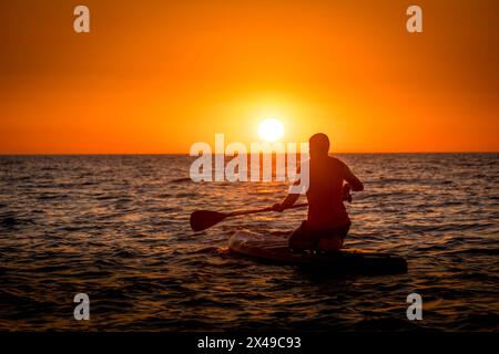 La personne sur la planche de flaque regardant le lever du soleil sur la mer Caspienne dans la capitale de la République du Daghestan dans le sud de la Russie. Banque D'Images