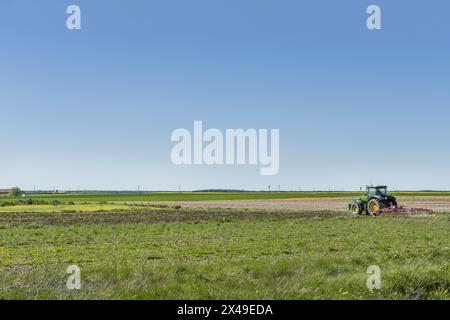 Un agriculteur avec son tracteur labourant un champ dans une zone plate de ​​Castilla, Espagne Banque D'Images