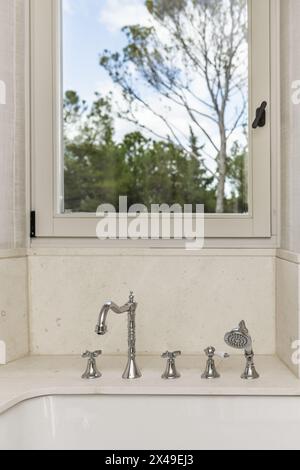 Une baignoire avec robinets de style vintage et une fenêtre en aluminium blanc et vue sur la forêt Banque D'Images