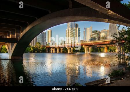 Sous le pont South Lamar à Austin, Texas, les eaux tranquilles de Town Lake et Lady Bird Lake reflètent les teintes dorées du coucher du soleil. Banque D'Images