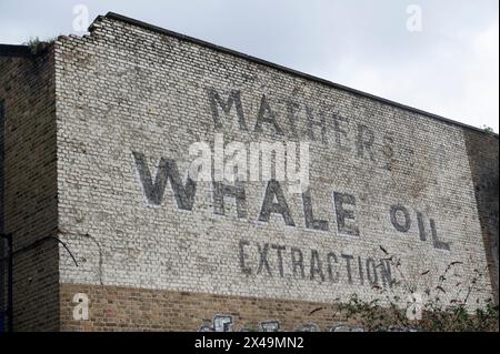 "Écriture fantôme" disant l'extraction d'huile de baleine de Mather sur le côté d'un vieil entrepôt, Trinity Buoy Wharf, East London. Banque D'Images