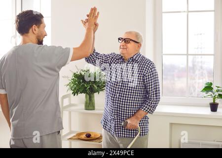 Médecin physiothérapeute, infirmière ou soignant avec homme âgé heureux donnant élevé cinq à la maison Banque D'Images