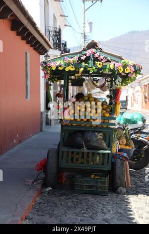 Stalle de fruits. Vendeur ambulant, Antigua, Guatemala, Amérique centrale. Chariot coloré de vendeur de rue, vendant ananas frais, mangue, papaye, raisins etc Banque D'Images