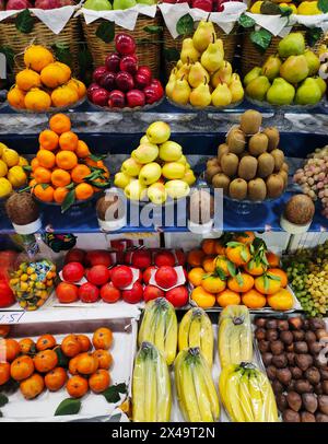 Pommes, poires, grenades, bananes, oranges, raisins kiwis kaki et autres fruits exposés Banque D'Images