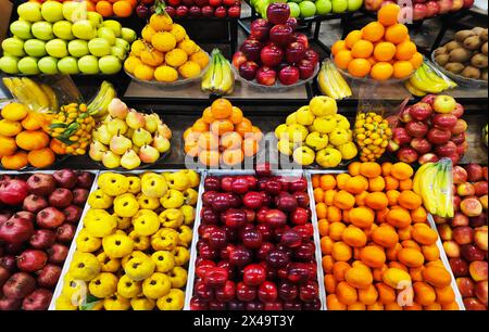 Pommes, poires, grenades, bananes, oranges, raisins kiwis kaki et autres fruits exposés Banque D'Images