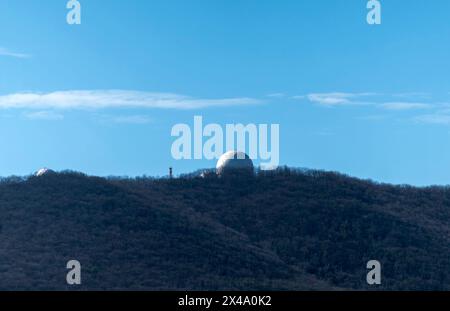 Dôme blanc de l'observatoire sur une montagne dans la forêt contre le ciel. Banque D'Images