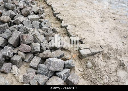 Pavage de rue avec pavés historiques en granit martelé, restauration de la surface de la rue de la ville, roches cubes Banque D'Images