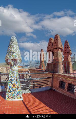 BARCELONE, ESPAGNE - 14 AVRIL 2024 : cheminées originales recouvertes de céramiques de différentes couleurs sur le toit du Palau Guell conçu par l'architecte an Banque D'Images