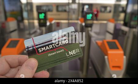 Un banlieue se rapproche de la barrière des billets à la gare de Peterborough pour se rendre à la gare de Kings Cross, Londres Banque D'Images