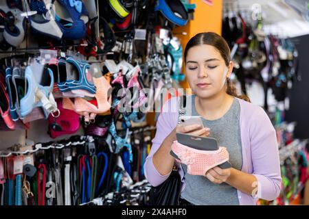 Une cliente qui lit le code-barres sur ses vêtements pour animaux avec son smartphone dans le magasin Banque D'Images