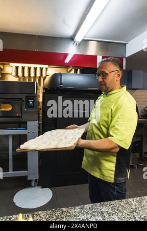 chef tenant la pâte à pizza avec une planche de bois pour la mettre dans un four. Photo de haute qualité Banque D'Images