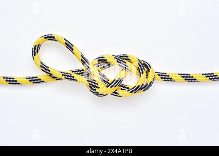 Figure 8 noeud de boucle directionnelle sur corde en nylon jaune et noir sur fond blanc. Banque D'Images