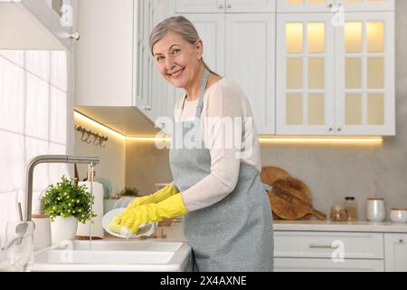 Bonne assiette de lavage de femme au foyer dans l'évier de cuisine Banque D'Images