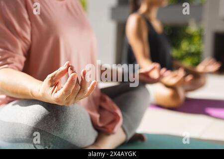 Grand-mère asiatique et petite-fille adolescente biraciale pratiquant le yoga en plein air, espace copie. Les deux portent des vêtements confortables, en se concentrant sur la position de la main Banque D'Images