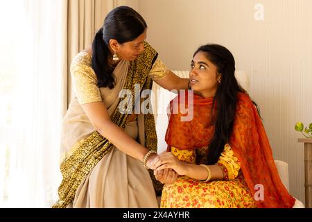 Mère indienne en sari réconfortant fille adolescente, à la fois en tenue traditionnelle. Mère aux cheveux noirs, fille aux yeux bruns, profitant du moment calme Banque D'Images