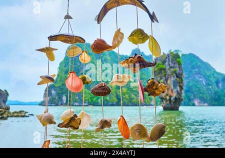 La célèbre tour karstique de Ko Ta pu se distingue sur fond vert de Ko Raya Ring Island, comme on le voit à travers les carillons de vent de coquille de mer au marché o Banque D'Images