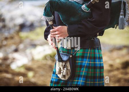 Un homme portant un kilt et tenant une pipe. L'homme est vêtu de vêtements écossais traditionnels et joue de la pipe. Concept de fierté culturelle et de heri Banque D'Images