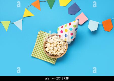 Bol de pop-corn savoureux, chapeau de fête et drapeaux pour la célébration de Festa Junina sur fond de couleur Banque D'Images