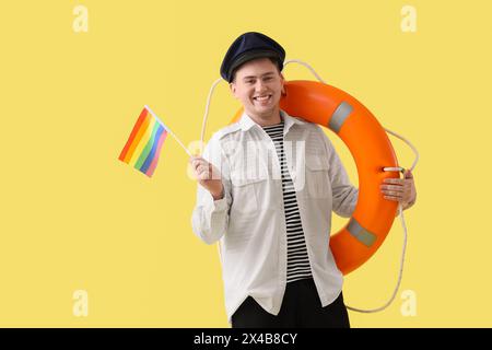 Marin masculin avec drapeau LGBT et bouée annulaire sur fond jaune Banque D'Images