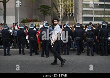 New York, États-Unis. 01 mai 2024. Un homme portant un keffiyeh passe devant des membres de la police de New York habillé en tenue anti-émeute debout devant l'Université de Fordham où des manifestants pro-palestiniens se sont rassemblés, New York, NY, 1er mai 2024. Des centaines de manifestants ont été arrêtés dans des collèges à travers les États-Unis alors que les manifestations se poursuivent sur la guerre israélo-Hamas. (Photo par Anthony Behar/Sipa USA) crédit : Sipa USA/Alamy Live News Banque D'Images