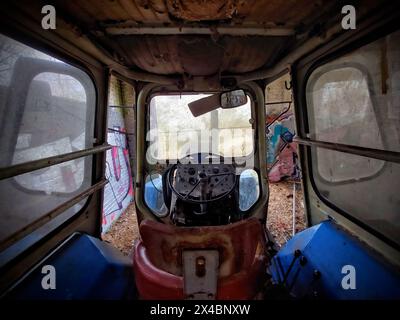 Cockpit d'un tracteur ancien et inutilisé dans une grange. Banque D'Images