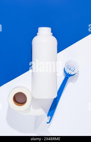 Sur un fond blanc et bleu, un détergent pour récipient en bouteille blanc non étiqueté décoré d'une brosse et d'un gant en papier. Espace pour l'emballage design. Househ Banque D'Images