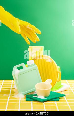 Bol, casserole et bouteille nettoyés avec des bulles de savon sur la surface décorée sur un fond vert. Kit de nettoyage pour différentes surfaces dans la cuisine, b Banque D'Images