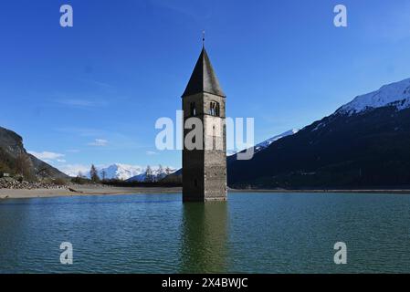 Graun im Vinschgau, Italien. Südtirol- und Italien-Urlauber kennen das Bild vom Reschensee, einem Bergsee, aus dem ein spitzer Kirchturm ragt. Es ist der Turm der Pfarrkirche : Katharina aus dem 14. Jahrhundert, die in den 50er Jahren mit dem Dorf Graun in den Fluten des Reschensees untergeging. Damals wurde ein Stausee gebaut, dem auch der Ort Reschen weichen musste. Foto : Kirchturm im Wasser bzw See *** Graun à Vinschgau, Italie Tyrol du Sud et Italie les vacanciers connaissent l'image du lac Reschen, un lac de montagne d'où s'élève une tour d'église pointue C'est la tour du XIVe siècle paris Banque D'Images