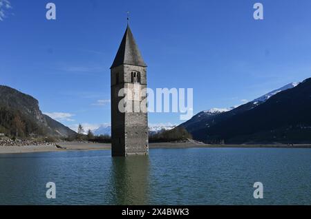 Graun im Vinschgau, Italien. Südtirol- und Italien-Urlauber kennen das Bild vom Reschensee, einem Bergsee, aus dem ein spitzer Kirchturm ragt. Es ist der Turm der Pfarrkirche : Katharina aus dem 14. Jahrhundert, die in den 50er Jahren mit dem Dorf Graun in den Fluten des Reschensees untergeging. Damals wurde ein Stausee gebaut, dem auch der Ort Reschen weichen musste. Foto : Kirchturm im Wasser bzw See *** Graun à Vinschgau, Italie Tyrol du Sud et Italie les vacanciers connaissent l'image du lac Reschen, un lac de montagne d'où s'élève une tour d'église pointue C'est la tour du XIVe siècle paris Banque D'Images