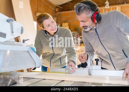 menuisier enseignant à l'apprenti comment couper le bois Banque D'Images