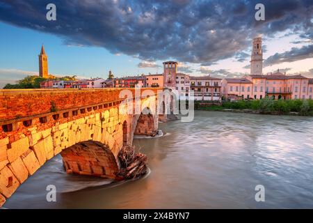 Vérone, Italie. Image de paysage urbain de la belle ville italienne de Vérone avec le pont de pierre au-dessus de la rivière Adige au coucher du soleil. Banque D'Images