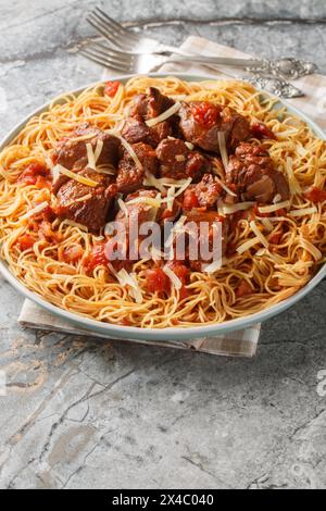 Kokkinisto bœuf braisé grec en sauce rouge avec des spaghettis de pâtes en gros plan sur l'assiette sur la table. Vertical Banque D'Images