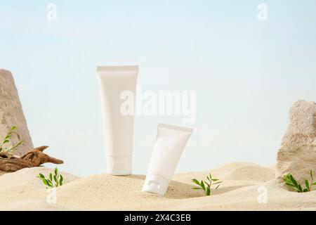 Scène Mockup pour la publicité cosmétique avec le concept de sable naturel. Deux tubes en plastique blanc affichés sur fond de sable avec brindilles sèches, herbe et pierres. Banque D'Images