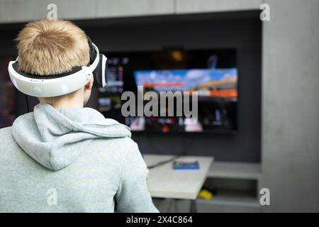 Osnabrück, Deutschland 29. Avril 2024 Im Bild : Ein Jugendlicher sitzt mit einer Virtual Reality brille, VR brille, vor einem Fernseher und spielt, zockt, ein Konsolenspiel auf einer Konsole. B ZEHN Niedersachsen *** Osnabrück, Allemagne 29 avril 2024 dans l'image Un jeune est assis devant une télévision avec des lunettes de réalité virtuelle, des lunettes VR, et joue, joue, un jeu de console sur une console B ZEHN Niedersachsen Copyright : xFotostandx/xGelhotx Banque D'Images