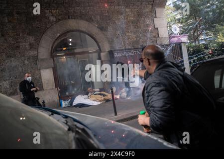 1er mai 2024, Paris, France. Un manifestant du 1er mai a déclenché des feux d'artifice près d'une zone de couchage de personnes sans foyer tandis qu'un autre exprime sa colère devant l'acte d'inattention. Une personne vêtue de noir se tient au-dessus de l'homme pour le protéger. Crédit : Jay Kogler/Alamy Live News Banque D'Images