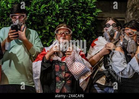 Tbilissi, Géorgie. 01 mai 2024. Une femme drapée d'un drapeau géorgien est vue debout à côté d'autres manifestants portant des masques à gaz pendant la manifestation devant le Parlement géorgien. Des milliers de personnes ont pris part à une manifestation contre la deuxième lecture d'un projet de loi qui a été voté pour faire avancer un projet de loi controversé sur les «agents étrangers» qui a déclenché des semaines de manifestations de masse dans la capitale, Tbilissi. (Photo de Nicholas Muller/SOPA images/SIPA USA) crédit : SIPA USA/Alamy Live News Banque D'Images