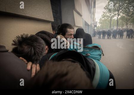 Paris, France. 01 mai 2024. Un groupe de manifestants se réunit pour se protéger du nuage de gaz lacrymogène pendant les manifestations de la fête du travail. Une journée pleine d'affrontements entre les groupes black-block, anarchistes et anticapitalistes, avec la police est devenue l'habitude lors de la célébration du 1er mai de la fête du travail à Paris, se plaignant du gouvernement du président Macron et de ses lois politiques et sociales. (Photo par Axel Miranda/SOPA images/SIPA USA) crédit : SIPA USA/Alamy Live News Banque D'Images