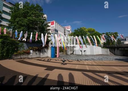 Enfant monte les escaliers sous la décoration Koinobori qui a été mise en place par la ville de Yokohama pour célébrer la Journée des enfants au Japon. La Journée des enfants, une fête japonaise qui honore la santé et le bonheur des enfants, est célébrée chaque année le 5 mai. En japonais, il est appelé : 'Kodomo no hi'. Les familles avec des garçons font voler d'énormes banderoles en forme de carpe (koinobori) à l'extérieur de leur maison et exposent des poupées de guerriers célèbres et d'autres héros à l'intérieur. La carpe symbolise la force et le succès ; selon une légende, une carpe a nagé en amont pour devenir un dragon. Les filles ont leur propre festival, appelé Hina Matsuri (poupée Fès Banque D'Images